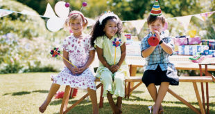 Two Girls and One Boy Sitting at a Garden Table at a Birthday Party