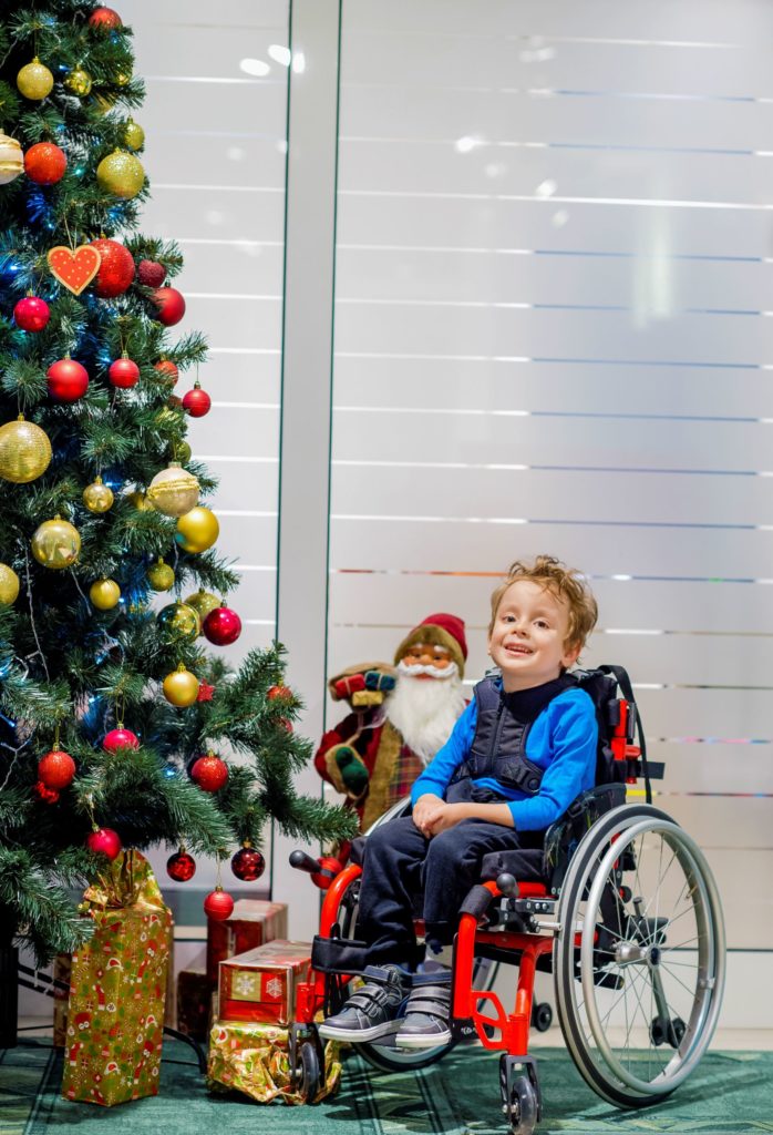 special needs child in wheelchair by Christmas tree