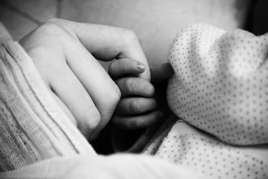 newborn is holding mother's finger for the first time
