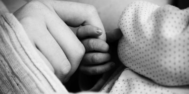 newborn is holding mother's finger for the first time
