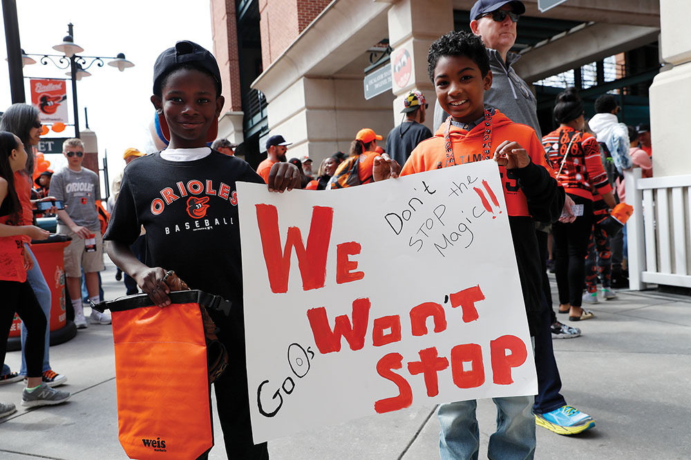 Kids hold up a "We Won't Stop" sign at an Orioles game