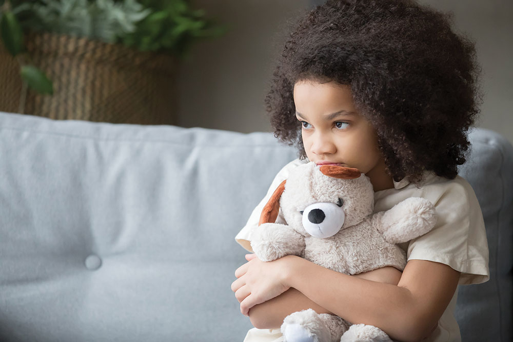 Upset lonely girl holding teddy bear looking away