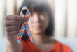Autistic child girl holding ribbon symbol of colorful pieces of jigsaw together for day of raise awareness about people with Autism Spectrum Disorder throughout the world.