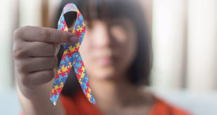 Autistic child girl holding ribbon symbol of colorful pieces of jigsaw together for day of raise awareness about people with Autism Spectrum Disorder throughout the world.