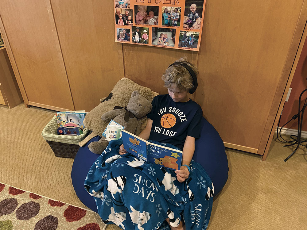 Child sits in a cozy space reading