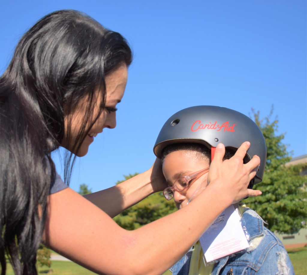 Can'd Aid volunteers place helmets on students at North Bend Elementar