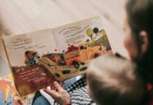 Stock photo of a woman reading a book to a toddler.