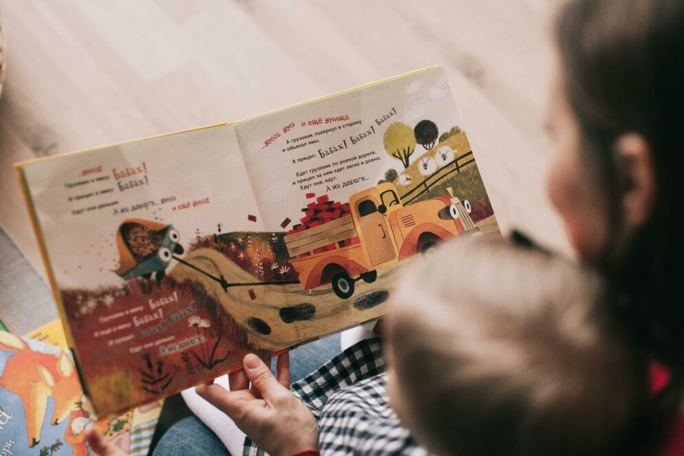 Stock photo of a woman reading a book to a toddler.