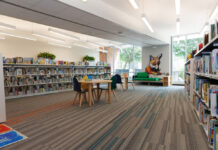 A brightly lit room with neat carpet, tables and chairs and bookshelves. There is a mural of a fox on the wall.