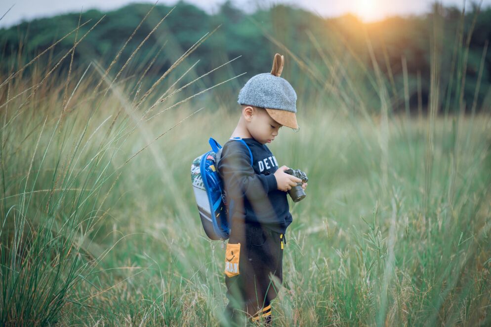 Child holding and looking at his camera in nature
