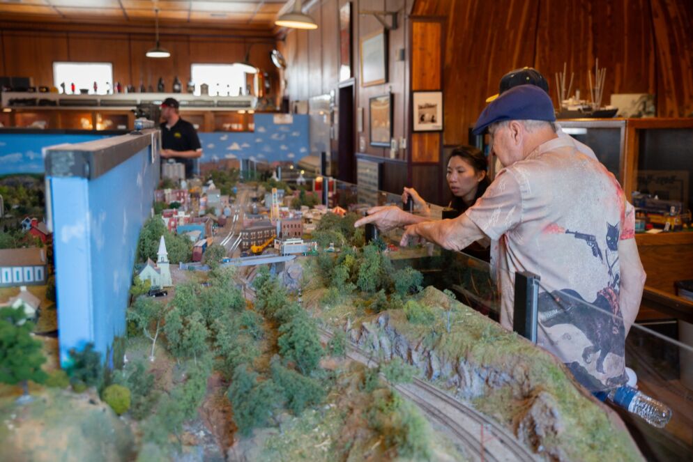 People standing over a model train set