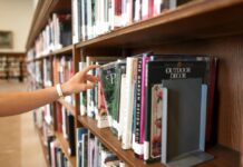 Person taking a book off the shelf at a library