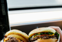 Two people holding burgers from Wayback Burger