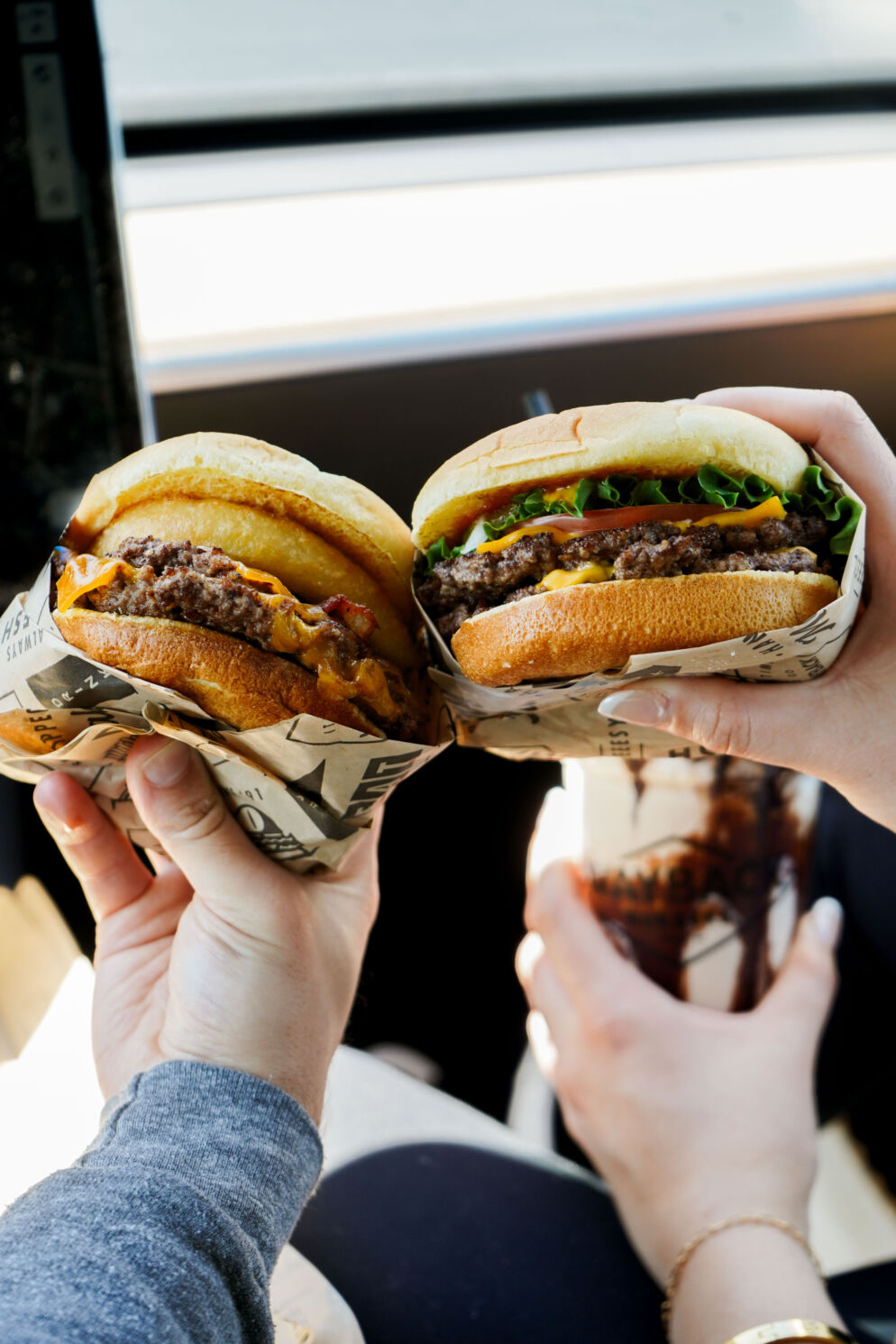 Two people holding burgers from Wayback Burger