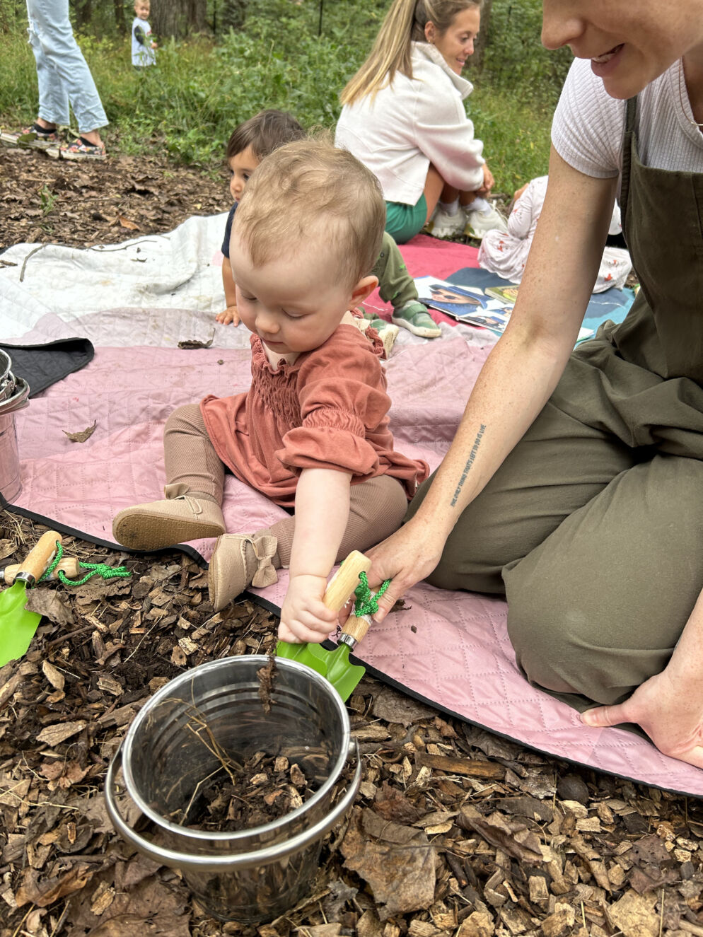 A baby and her parent playing in the dirt