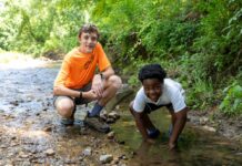 Two boys crouching in a stream