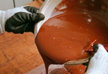 Person pouring melted chocolate into bar-shaped molds
