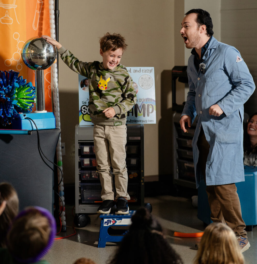 Fenn Vandy with Science Guys of Baltimore; a child stands on a stool to touch a globe as a part of the Science Guys of Baltimore summer camp.