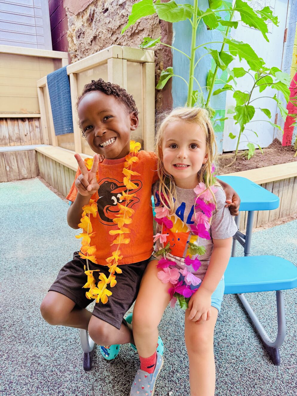 Two kids stand together at Summer at Garrison Forest, both wearing Hawaiian lays.