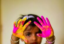 A child shows off his hands covered in colored powder after a Holi celebration