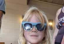 Girl wearing sunglasses holding a kitten