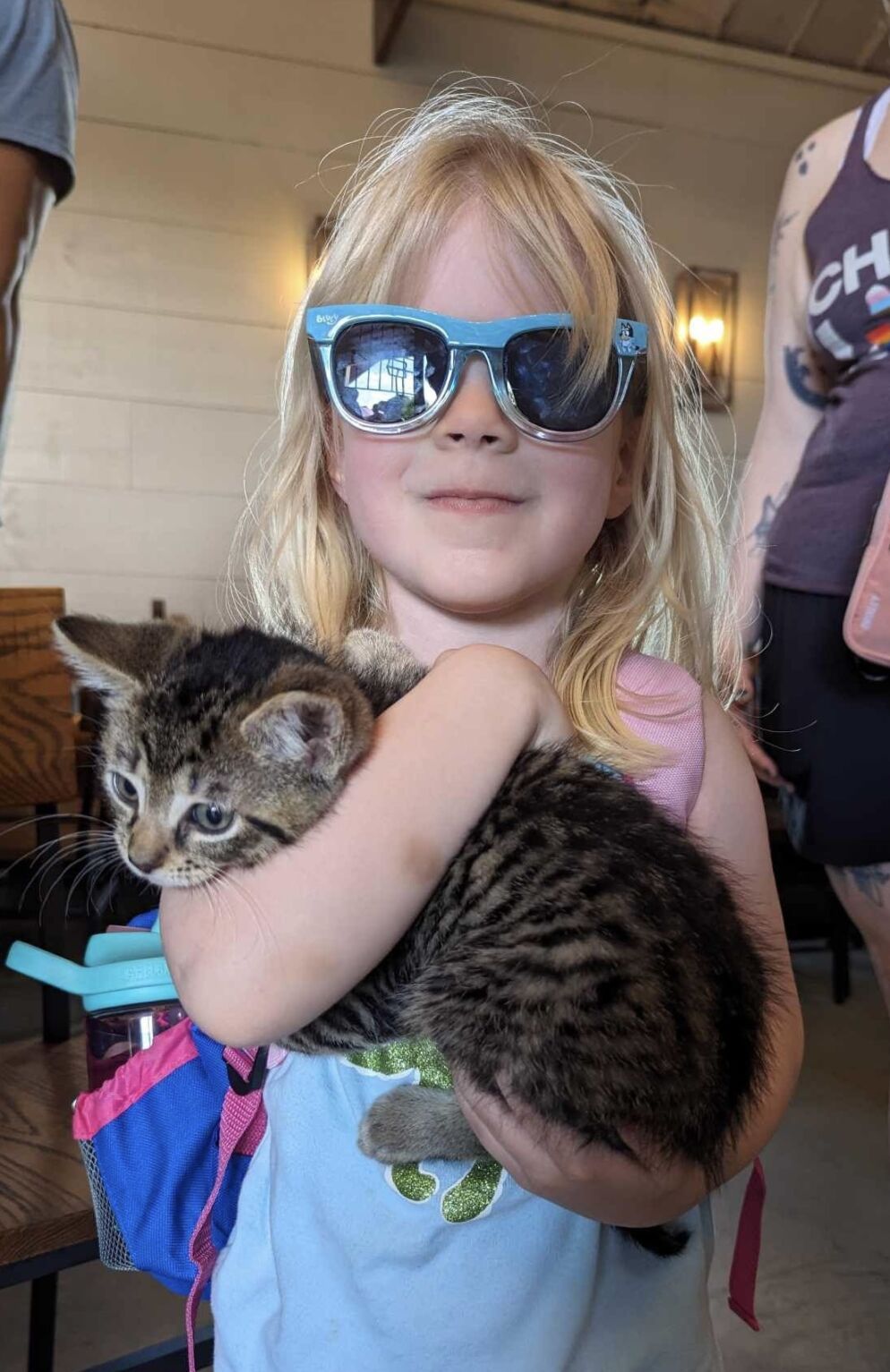 Girl wearing sunglasses holding a kitten