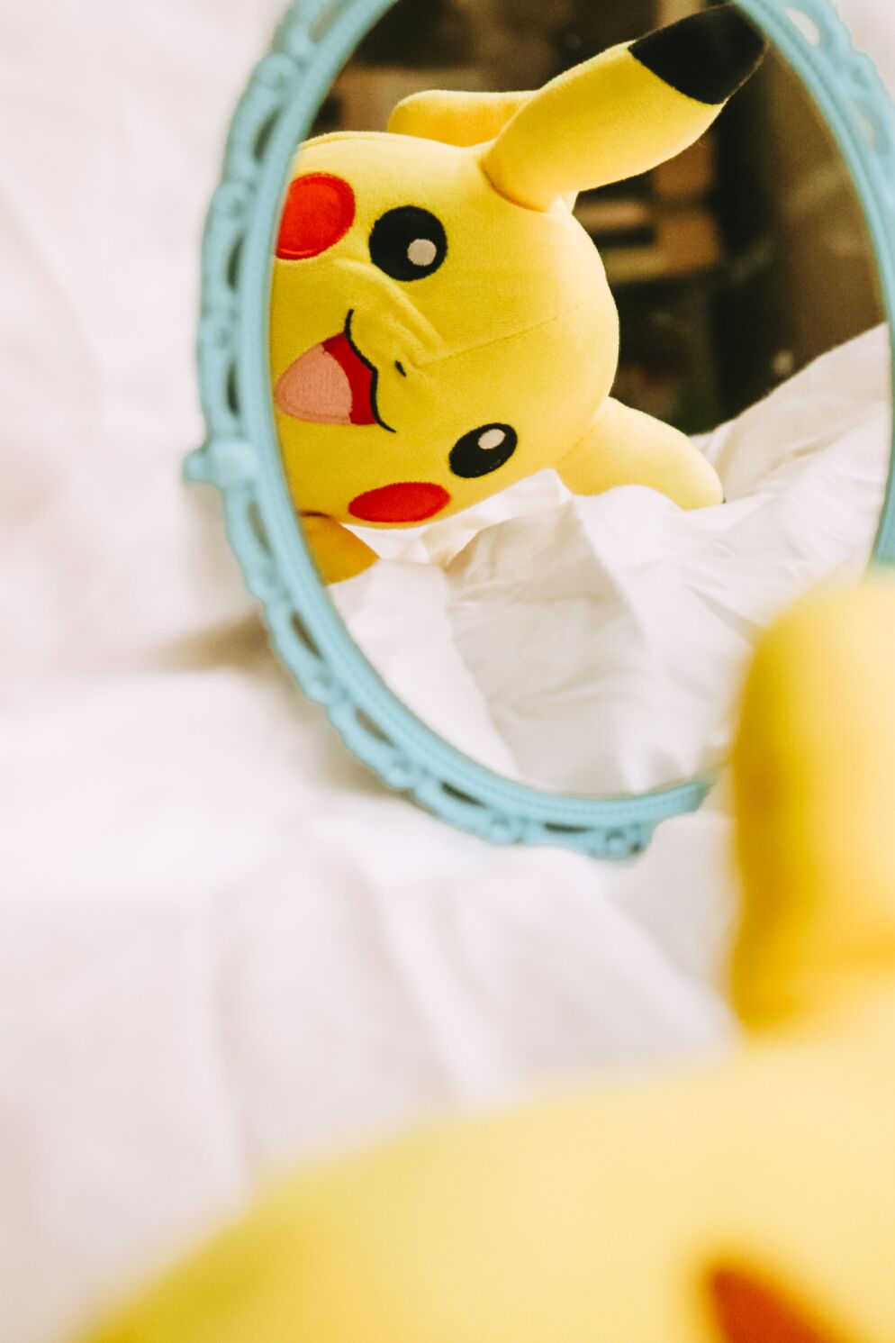 A Pikachu plushie looking in a mirror