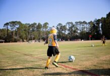 How To Prepare Kids for Fall Sports Tryouts A school-age girl practices kicking a soccer ball.