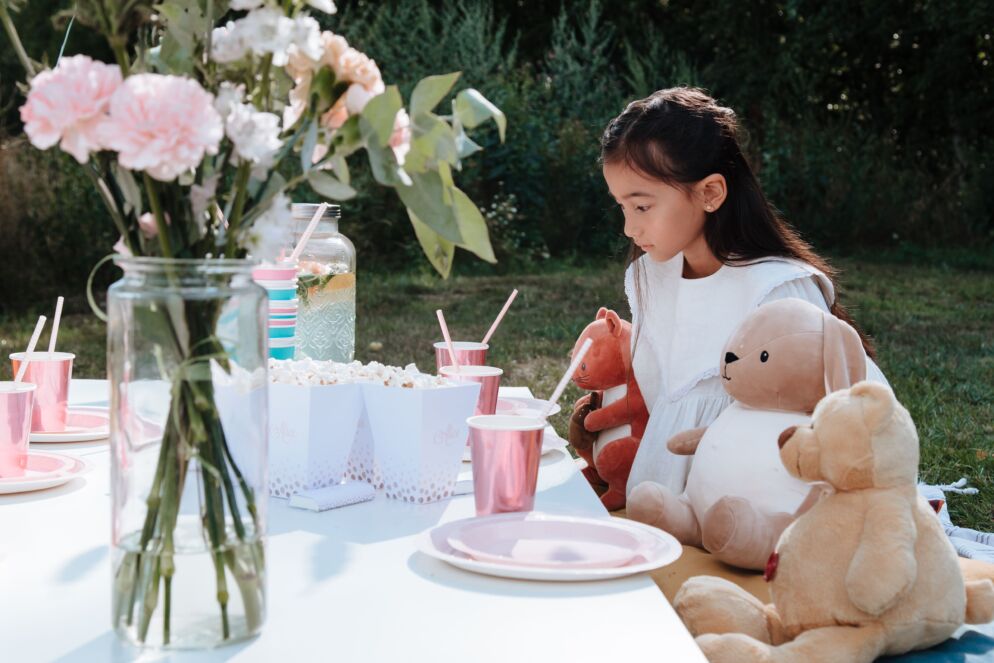 A girl having a picnic with several stuffed animals