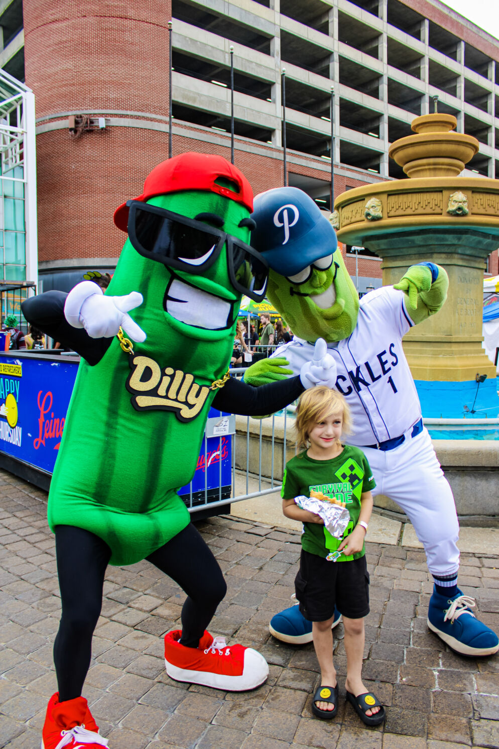 A boy poses with pickle mascots at The Big Dill Festival 