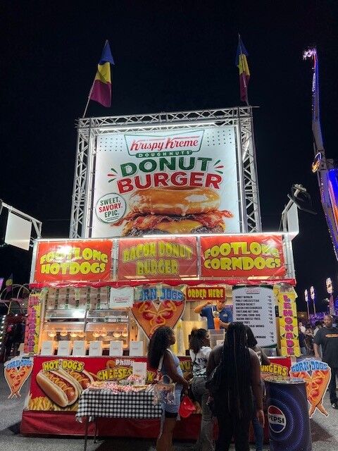 A large illuminated sign for Donut Burger at the Krispy Kreme stand at the fair